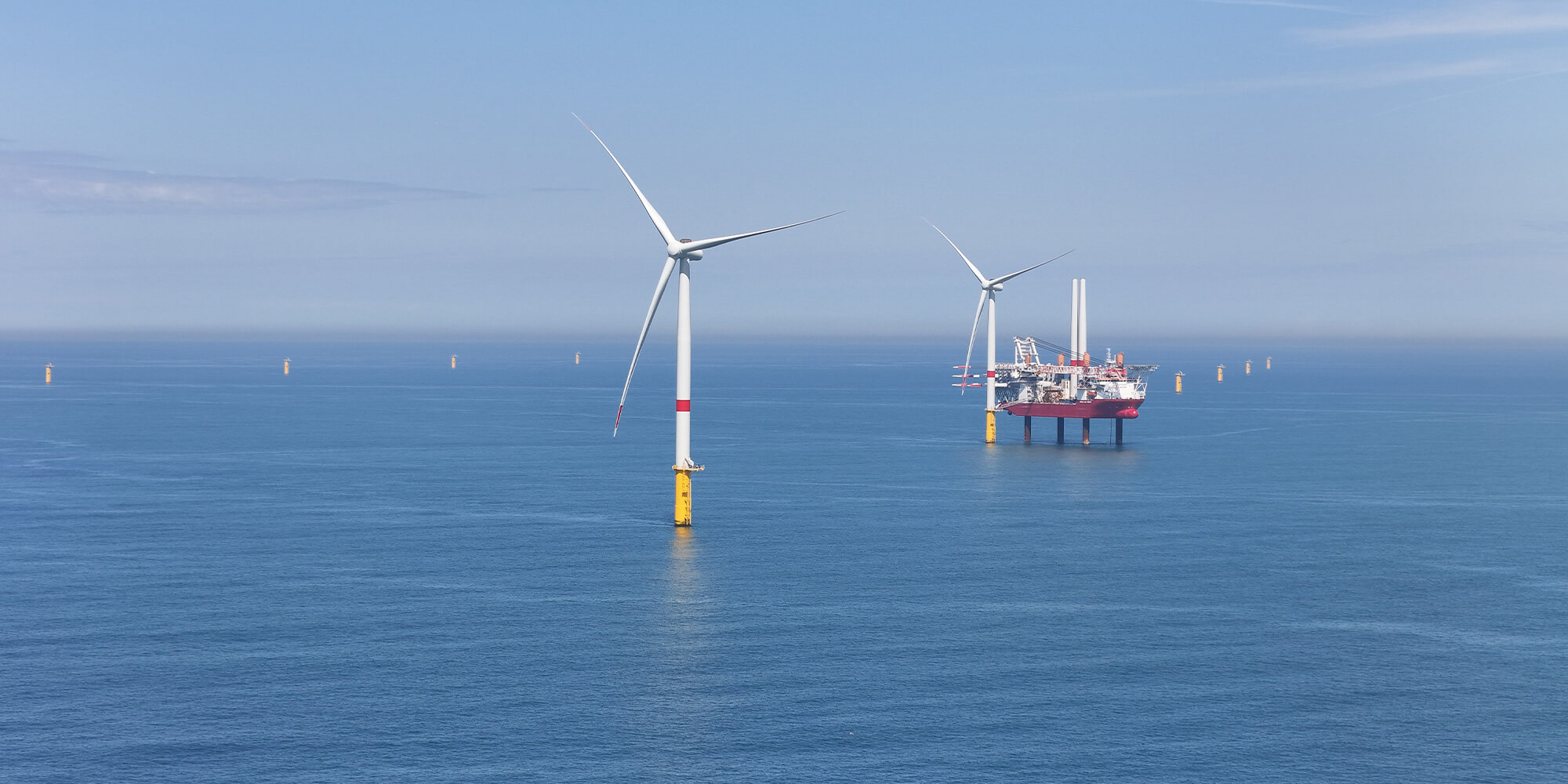 Offshore wind turbines with a service vessel in a calm sea under a clear sky