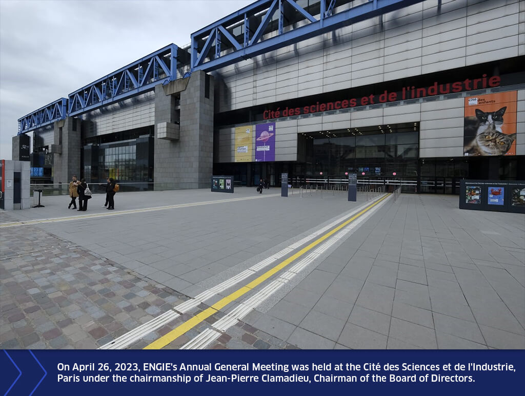 Main facade of the Cité des sciences et de l’industrie in Paris, showing the glass entrance, a few visitors on the forecourt, and a banner mentioning ENGIE’s Annual General Meeting on April 26, 2023.