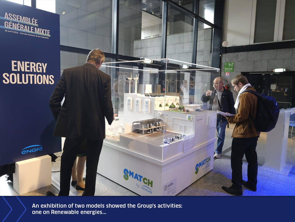 Visitors viewing a scale model exhibition on renewable energy solutions during ENGIE’s General Assembly, with interactive displays and presentation panels.