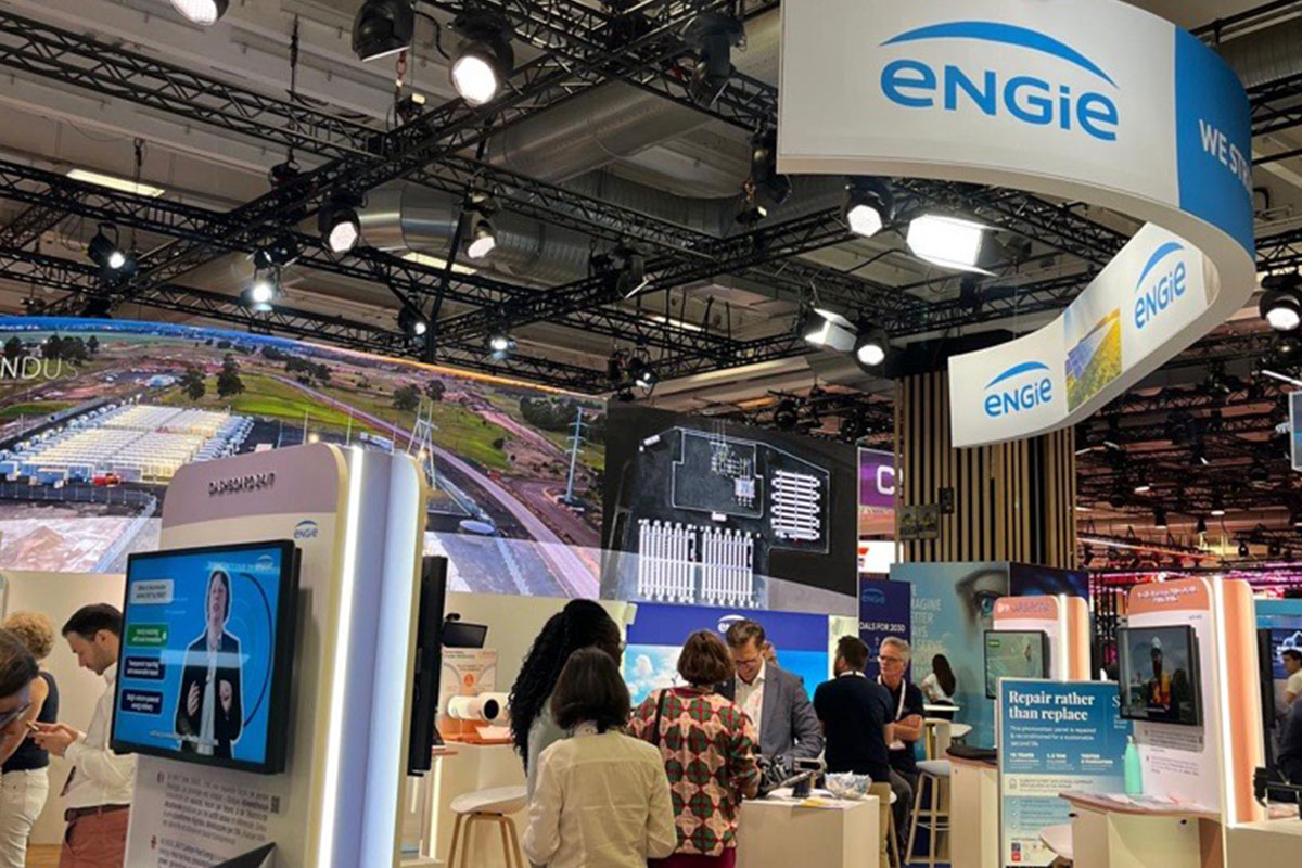Exhibition booth with ENGIE branding, digital screens, visitors and interactive displays