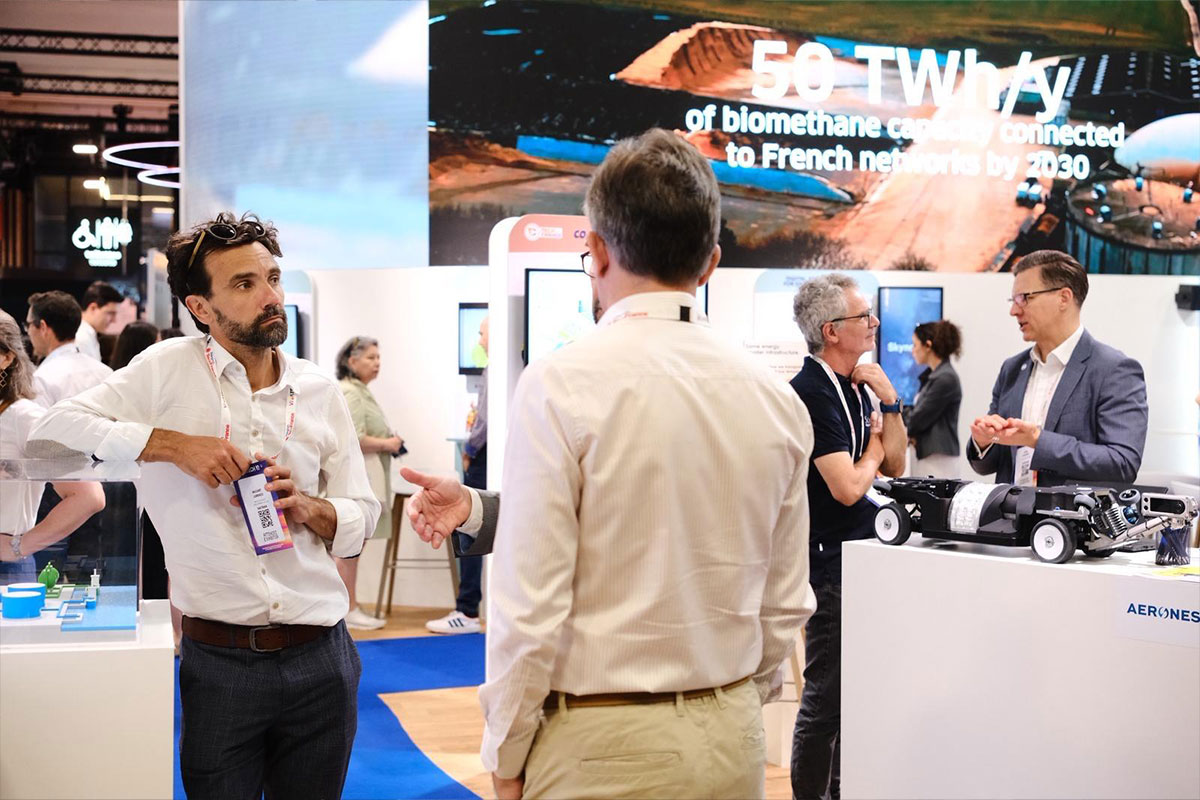 People networking at an energy technology exhibition booth with biomethane display