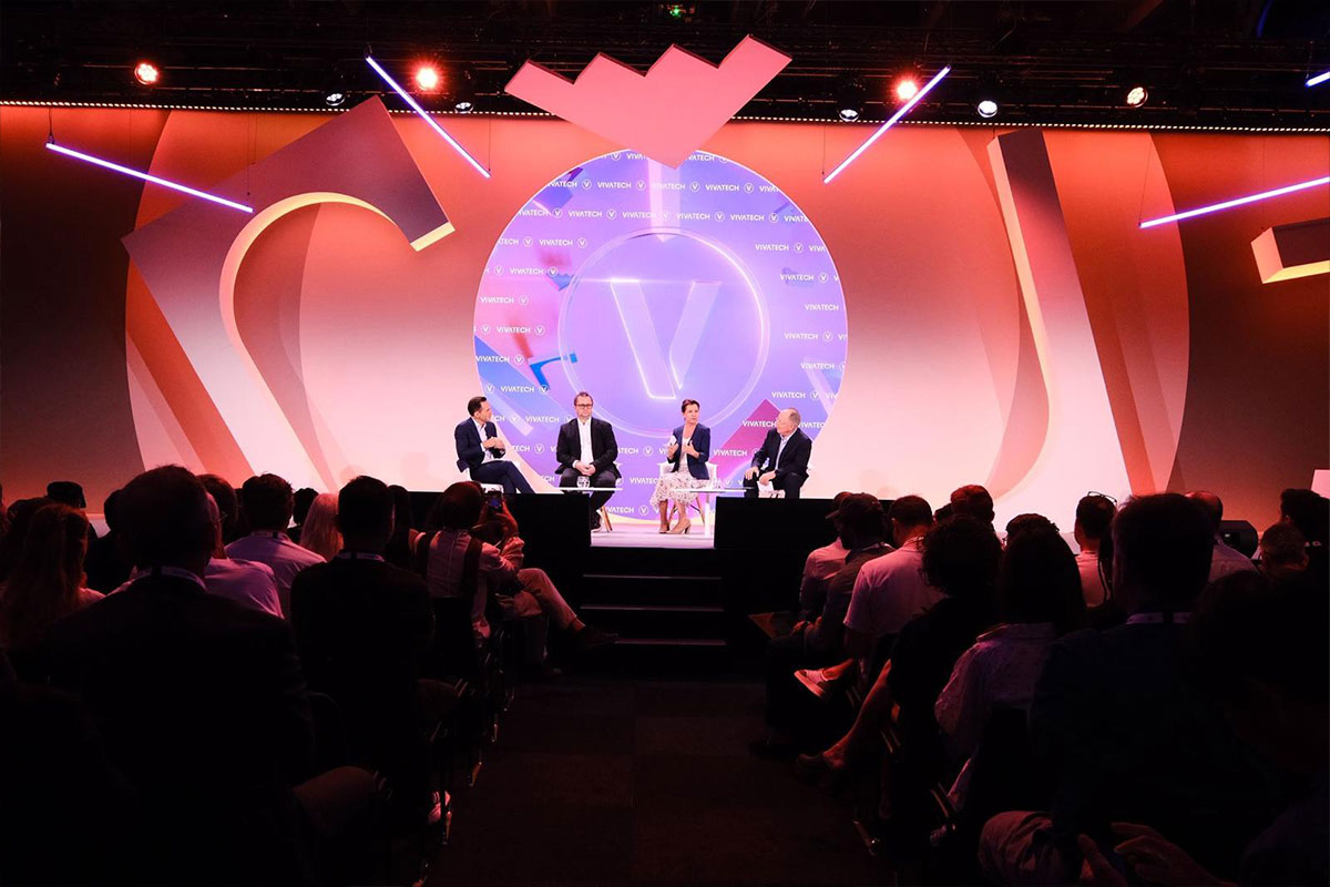 Panel discussion with four speakers on stage at a tech event, audience in foreground