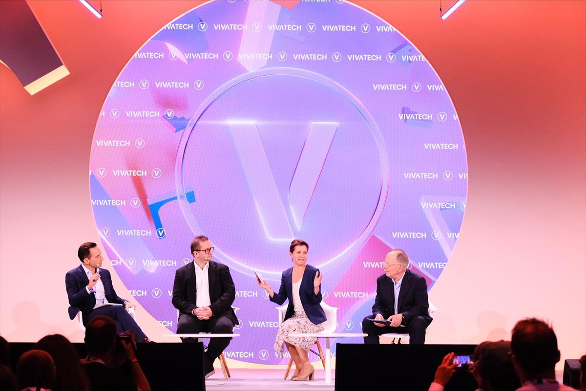 Four speakers seated on stage during a panel discussion at VivaTech event with large illuminated backdrop